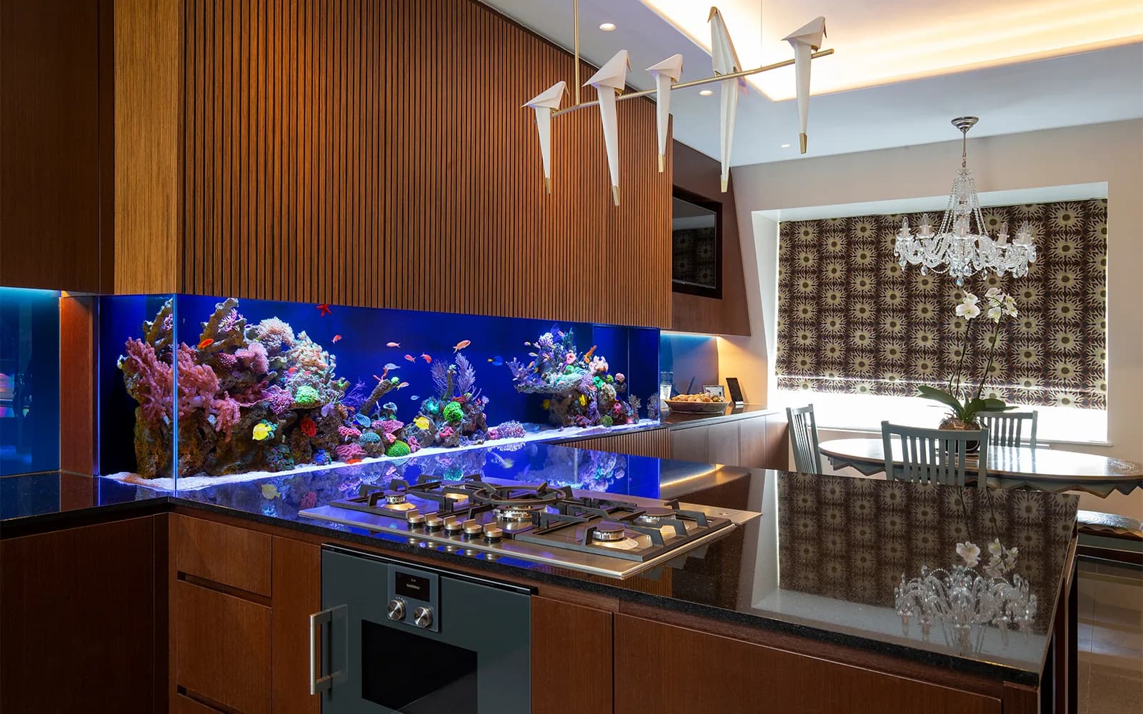 A long reef aquarium built into the cabinetry of a wood-panelled kitchen.