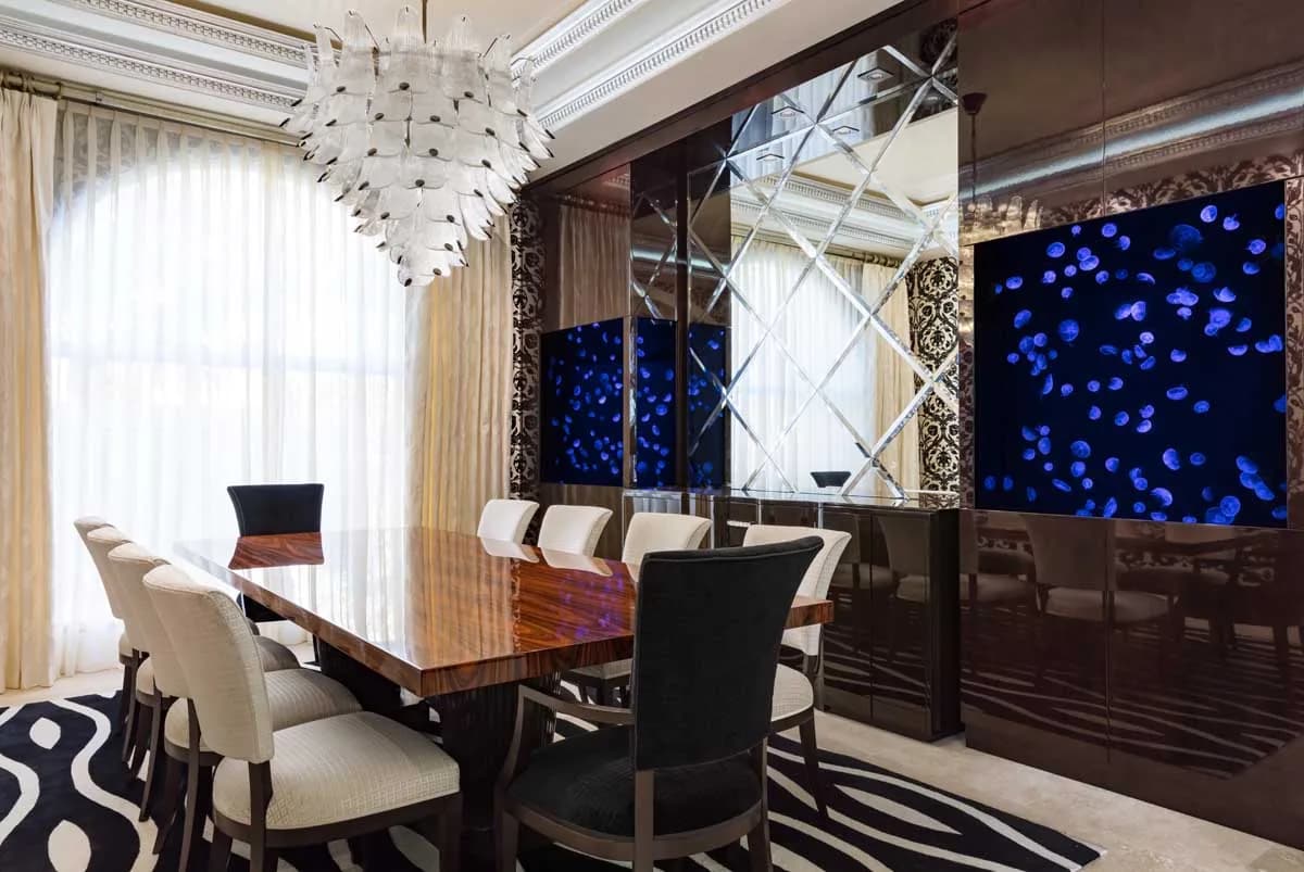 A blue reef aquarium beside mirrored panelling in a formal dining room.